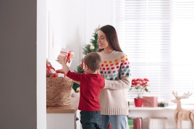 Mother and son with Christmas gifts at home. Advent calendar in basket