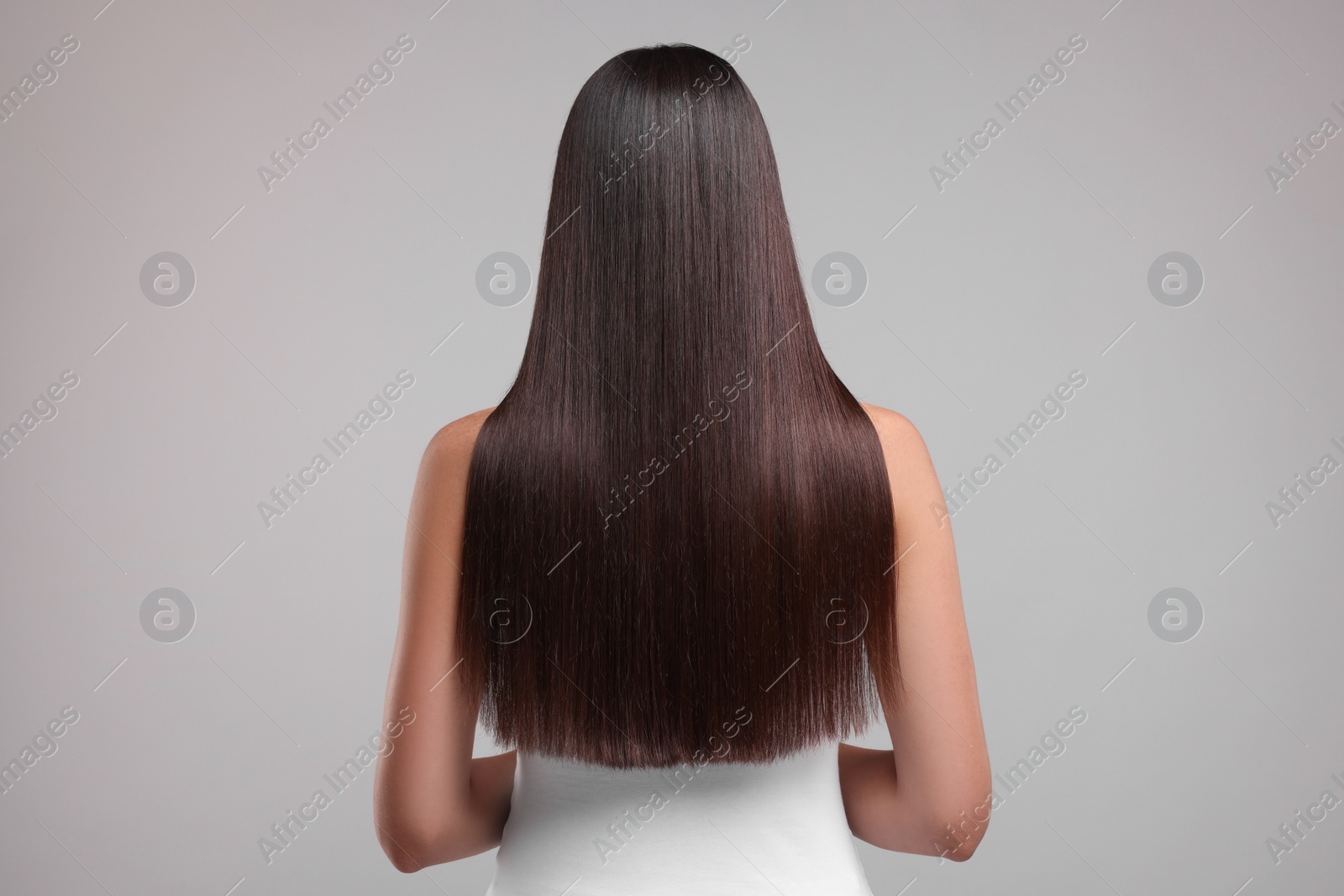 Photo of Woman with healthy hair after treatment on light gray background, back view