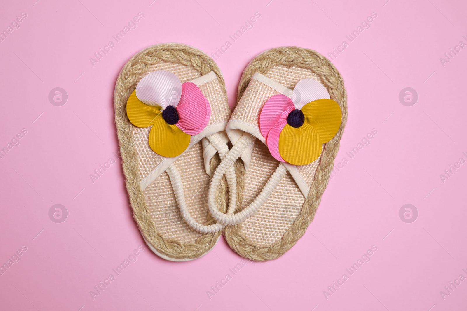 Photo of Cute baby shoes on pink background, flat lay