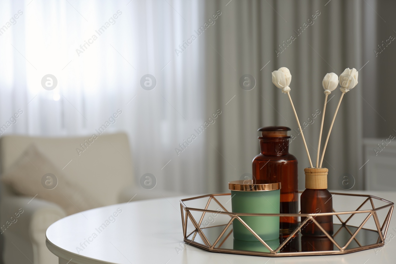 Photo of Air reed freshener and candle on white table in room, space for text