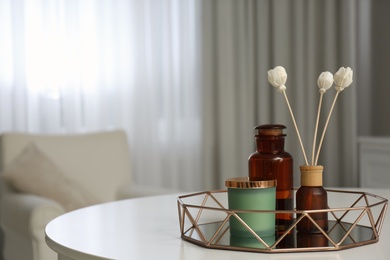 Photo of Air reed freshener and candle on white table in room, space for text