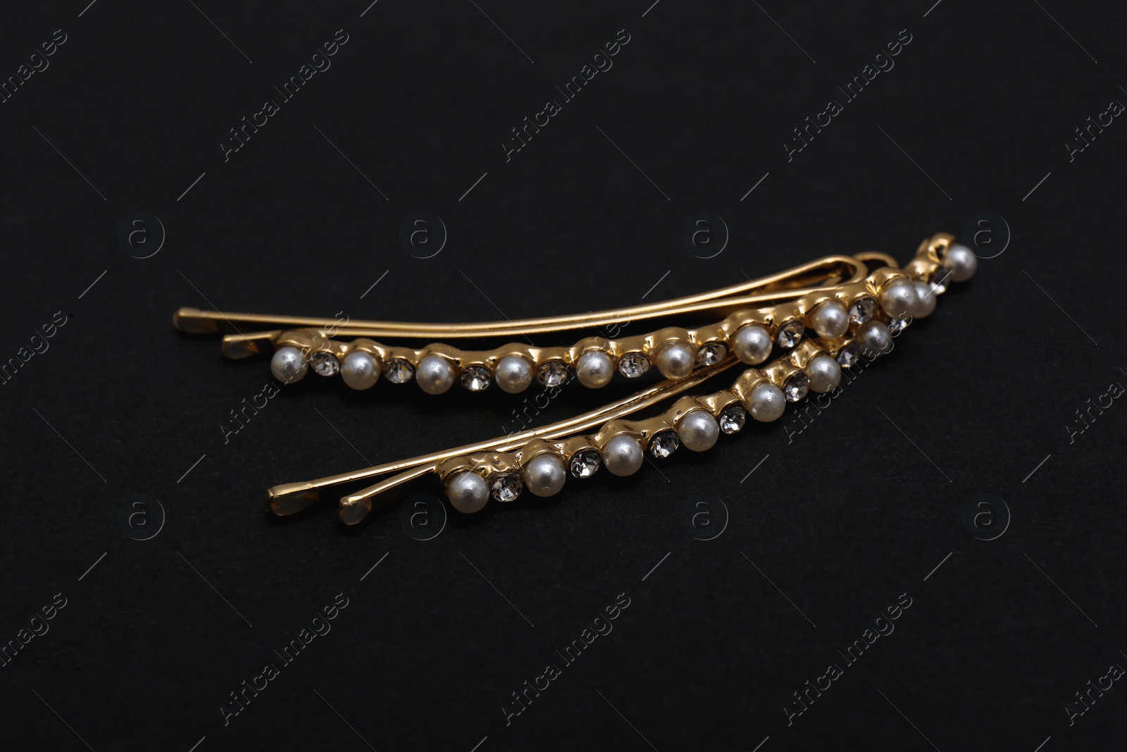 Photo of Beautiful gold hair pins on black background