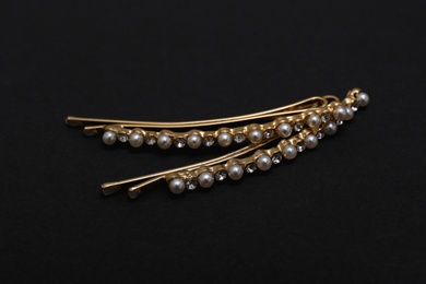 Photo of Beautiful gold hair pins on black background