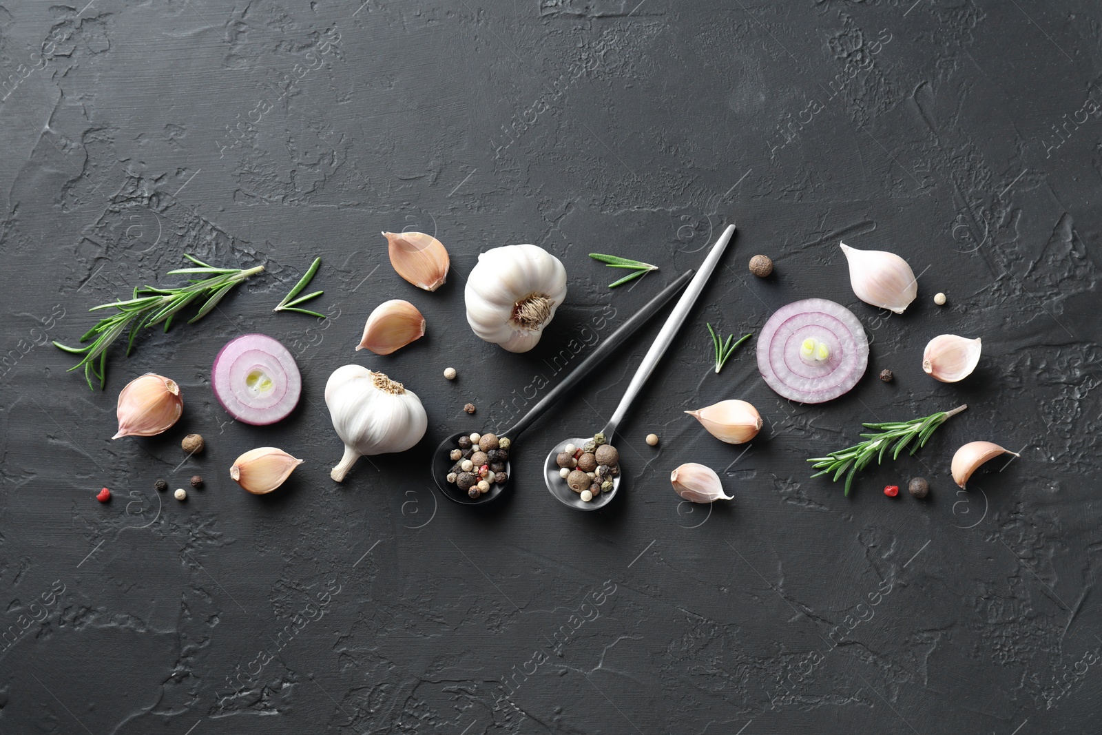 Photo of Fresh raw garlic, onion rings and spices on black table, flat lay