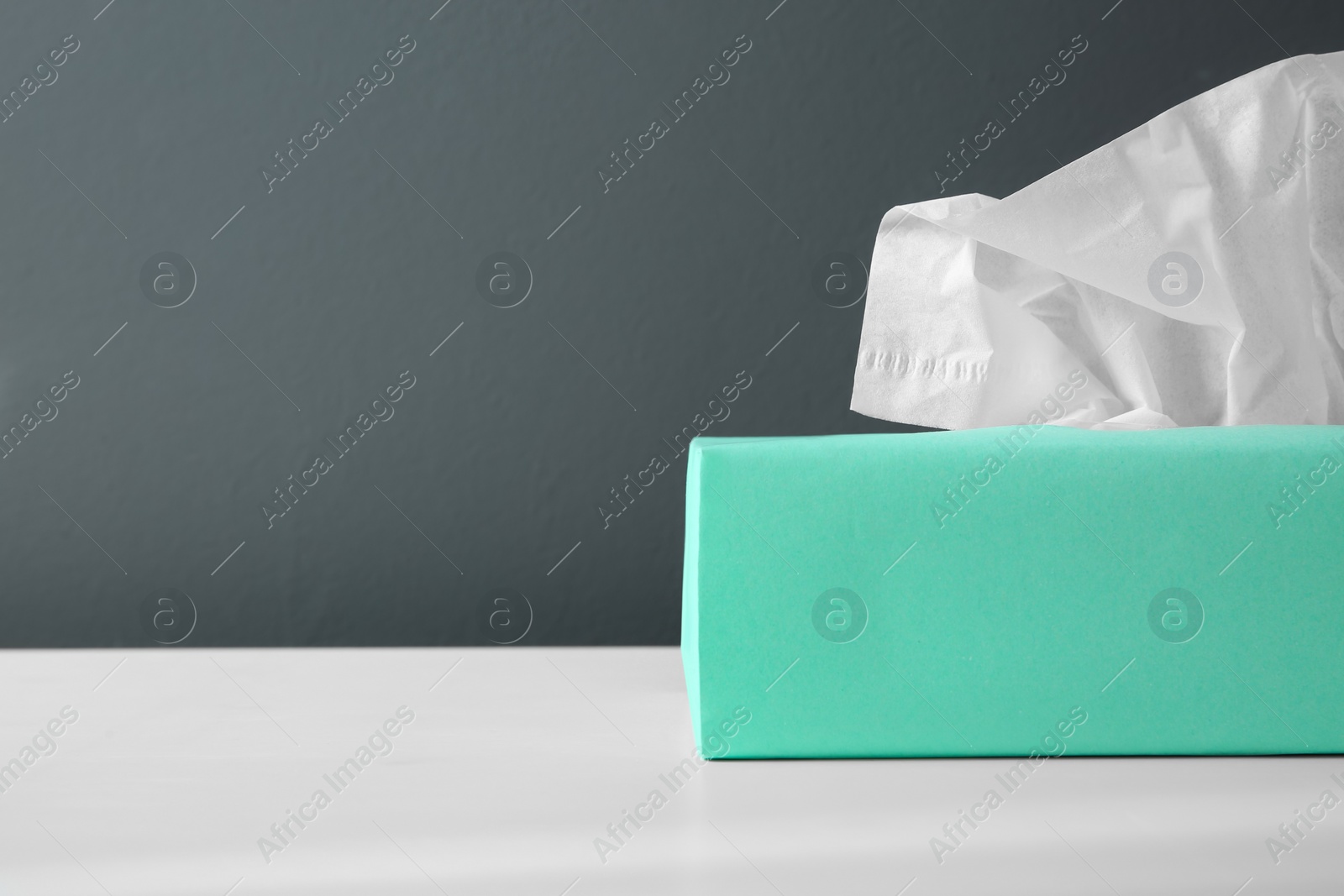 Photo of Box with paper tissues on white table. Space for text