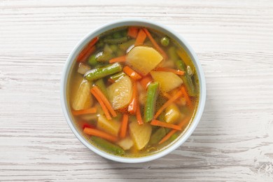 Photo of Bowl of tasty turnip soup on white wooden table, top view