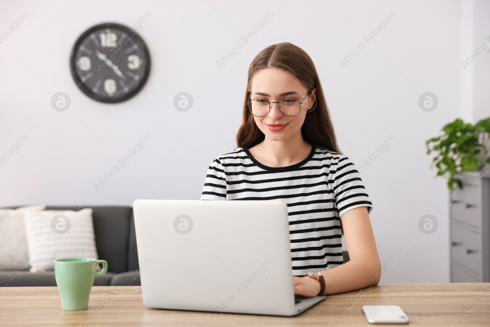 Photo of Happy young woman with laptop at table indoors