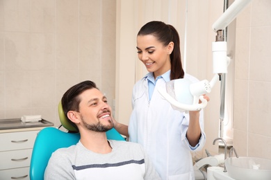 Photo of Professional dentist working with patient in modern clinic