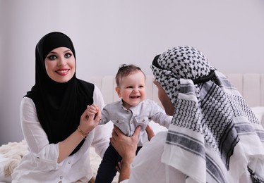 Photo of Happy Muslim family with little son in bedroom