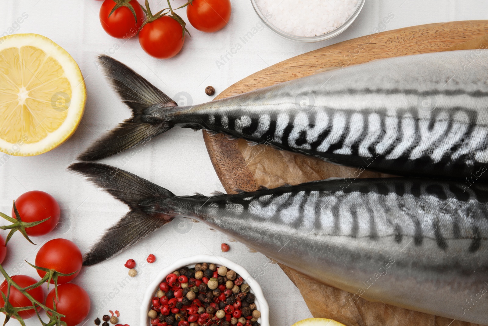 Photo of Raw mackerel, tomatoes and lemon on white table, flat lay