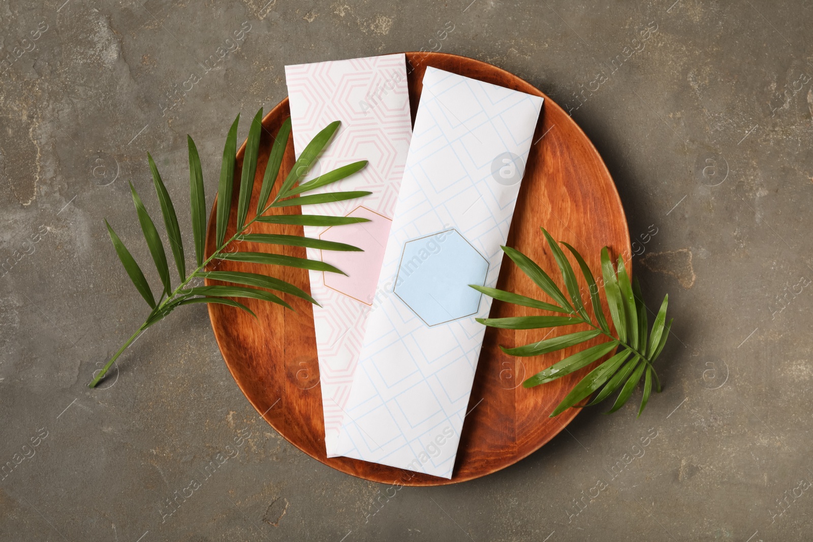 Photo of Scented sachets and green leaves on grey table, flat lay