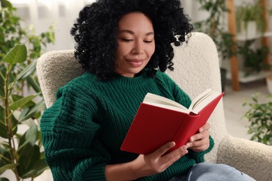 Relaxing atmosphere. Woman reading book in armchair in room with beautiful houseplants