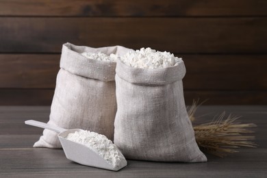 Photo of Sacks with flour and wheat spikes on wooden background