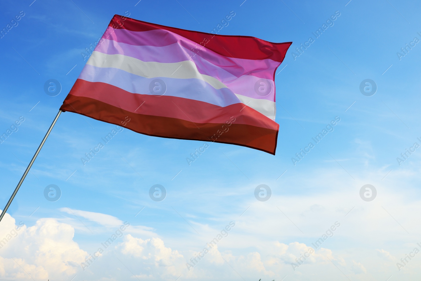 Photo of Bright lesbian flag fluttering against blue sky