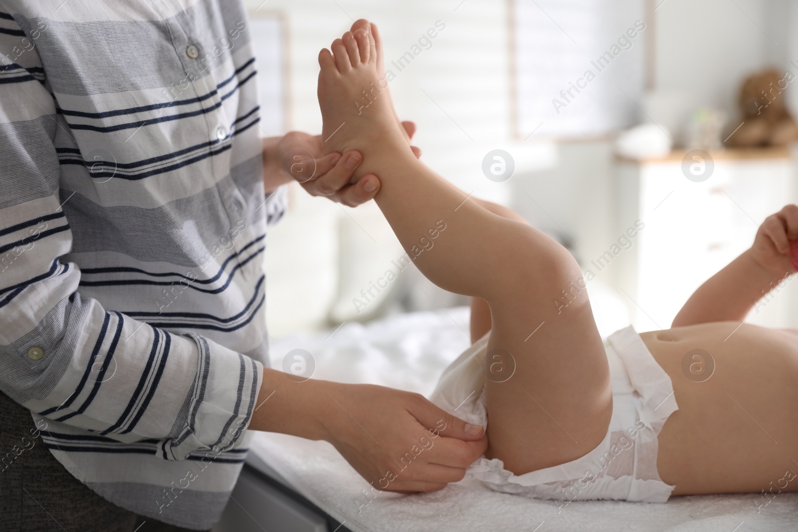 Photo of Mother changing baby's diaper on table at home, closeup