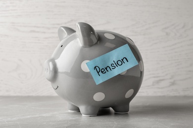 Piggy bank and paper with word PENSION on table