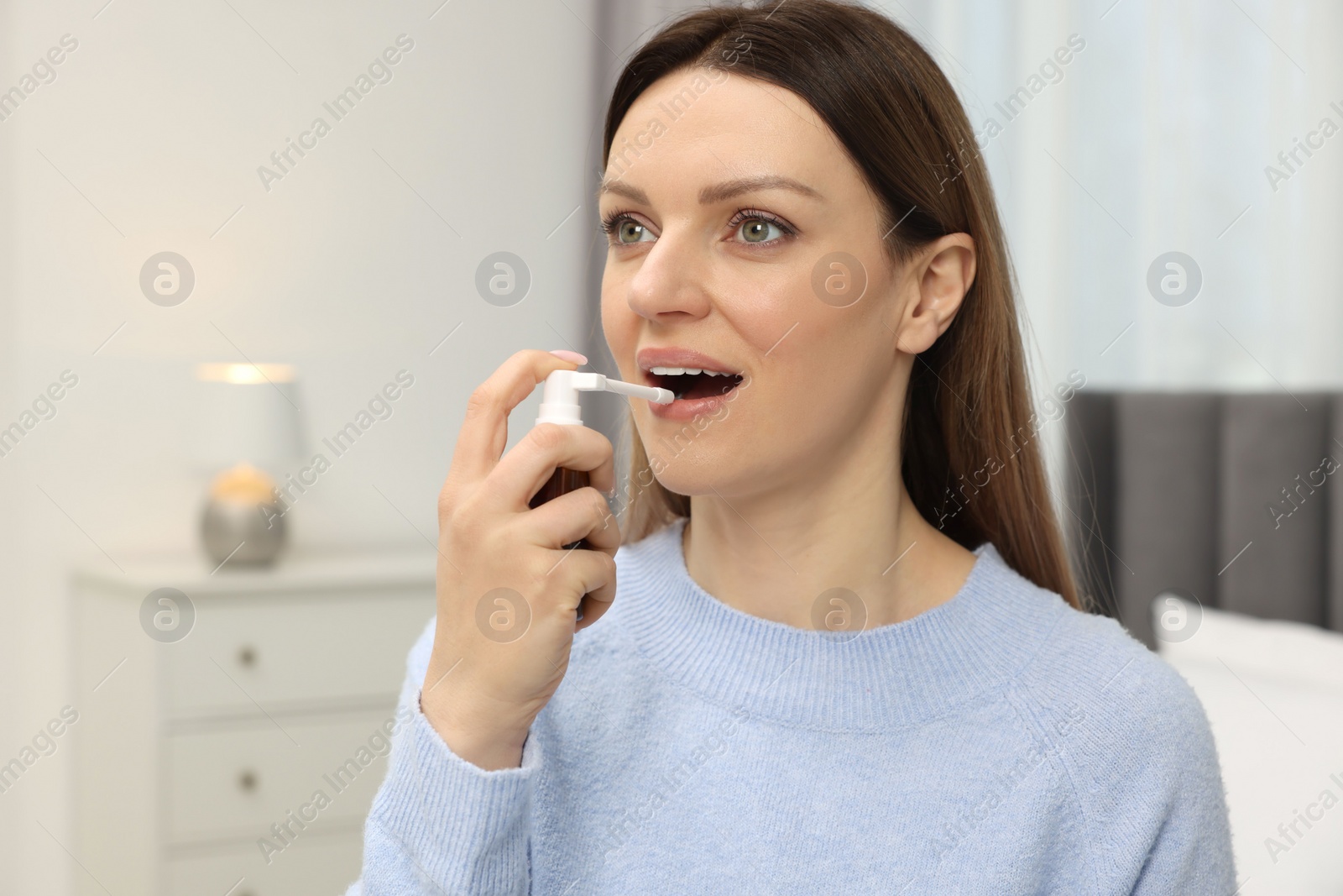 Photo of Adult woman using throat spray in bedroom, space for text