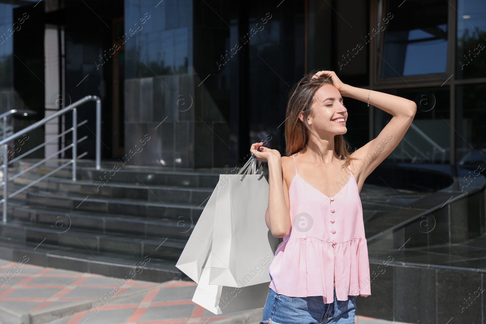 Photo of Happy young woman with shopping bags outdoors