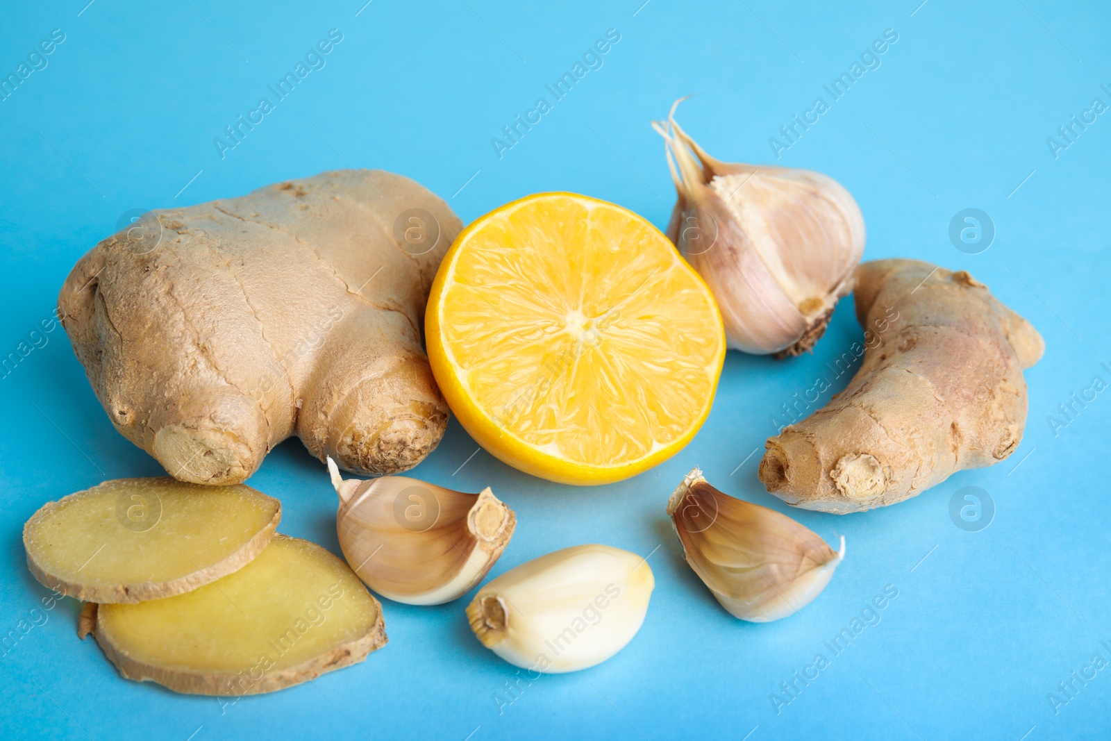 Photo of Fresh garlic and other natural cold remedies on light blue background