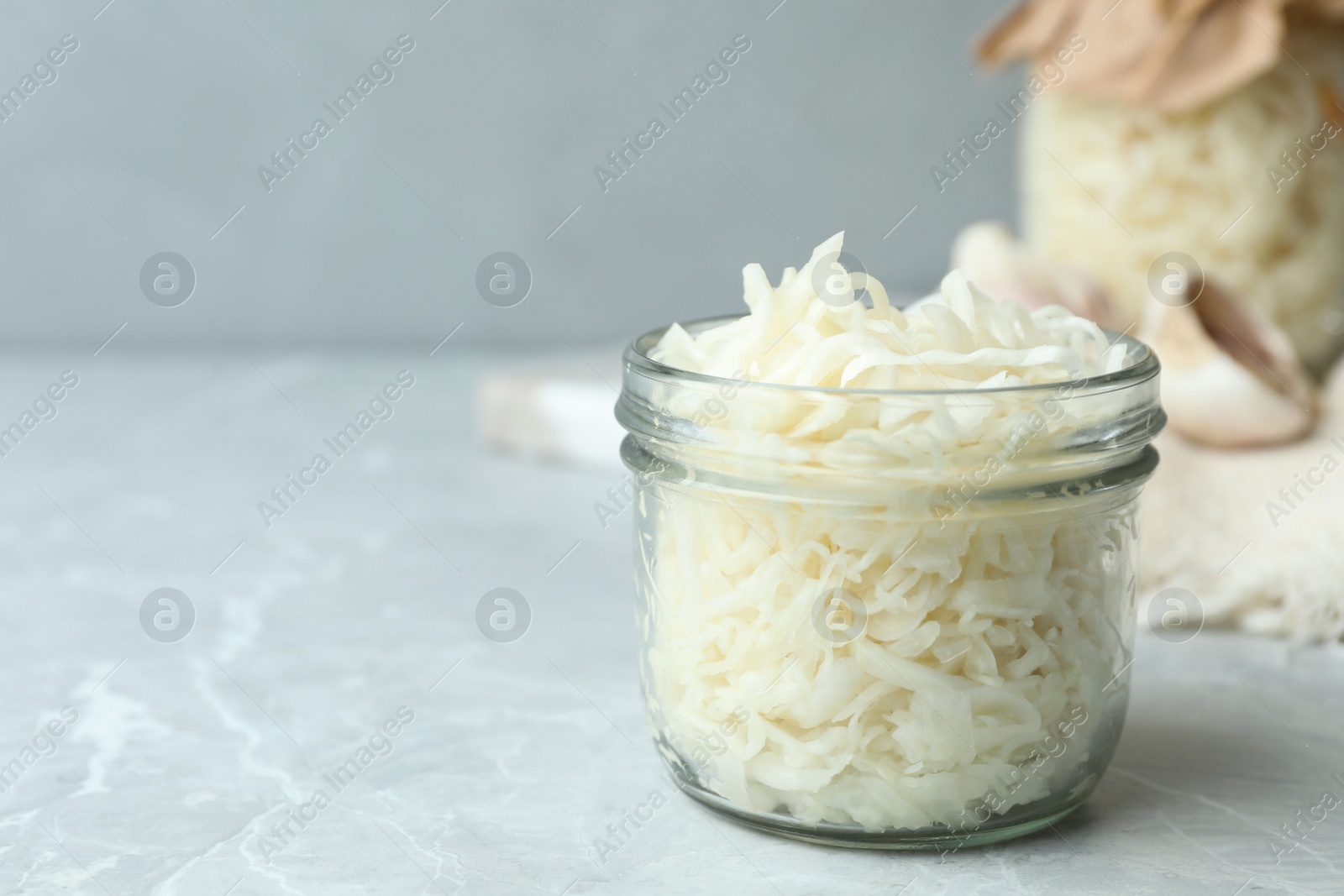 Photo of Tasty fermented cabbage on light grey marble table, closeup