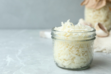 Tasty fermented cabbage on light grey marble table, closeup