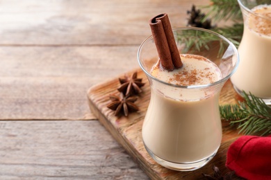 Photo of Delicious Christmas liqueur on wooden table, closeup. Space for text