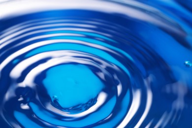 Photo of Splash of clear water on blue background, closeup