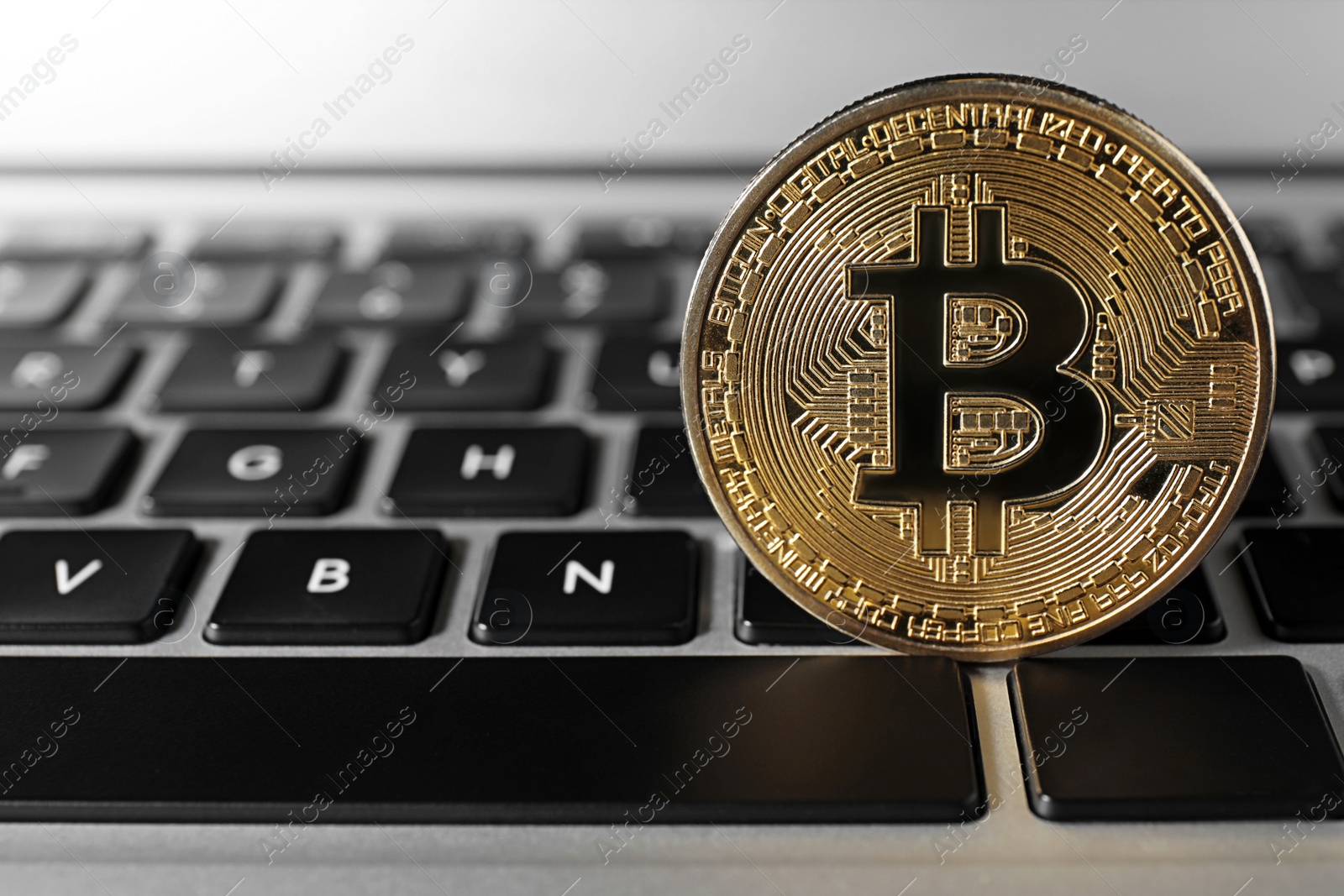 Photo of Golden bitcoin on computer keyboard, space for text. Digital currency