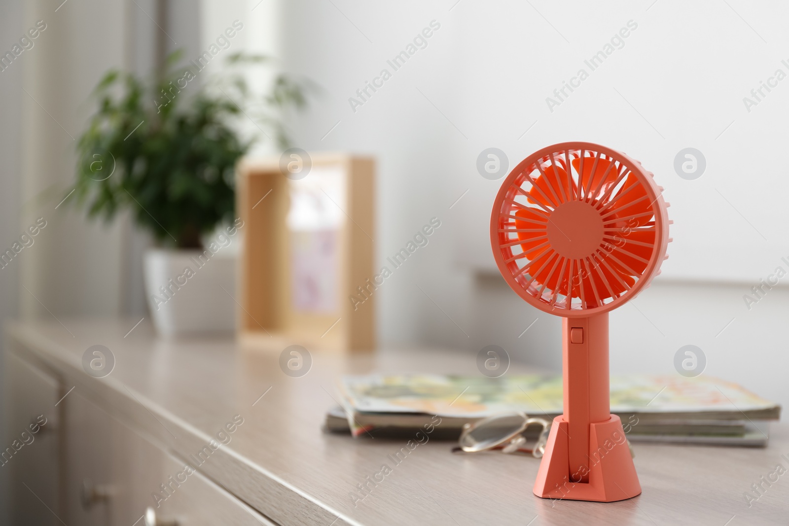 Photo of Modern portable fan on wooden table indoors, space for text. Summer heat