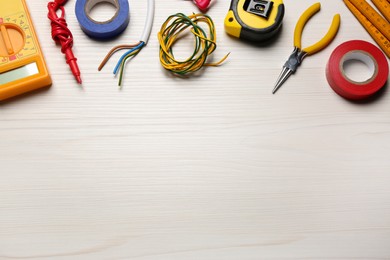 Photo of Different wires and electrician's tools on white wooden table, flat lay. Space for text