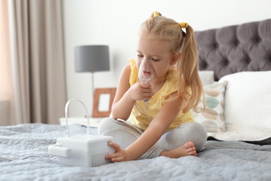 Little girl using asthma machine in bedroom