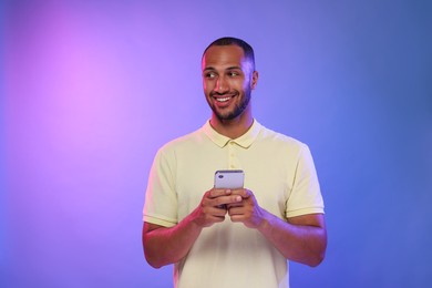 Photo of Happy man sending message via smartphone on color background