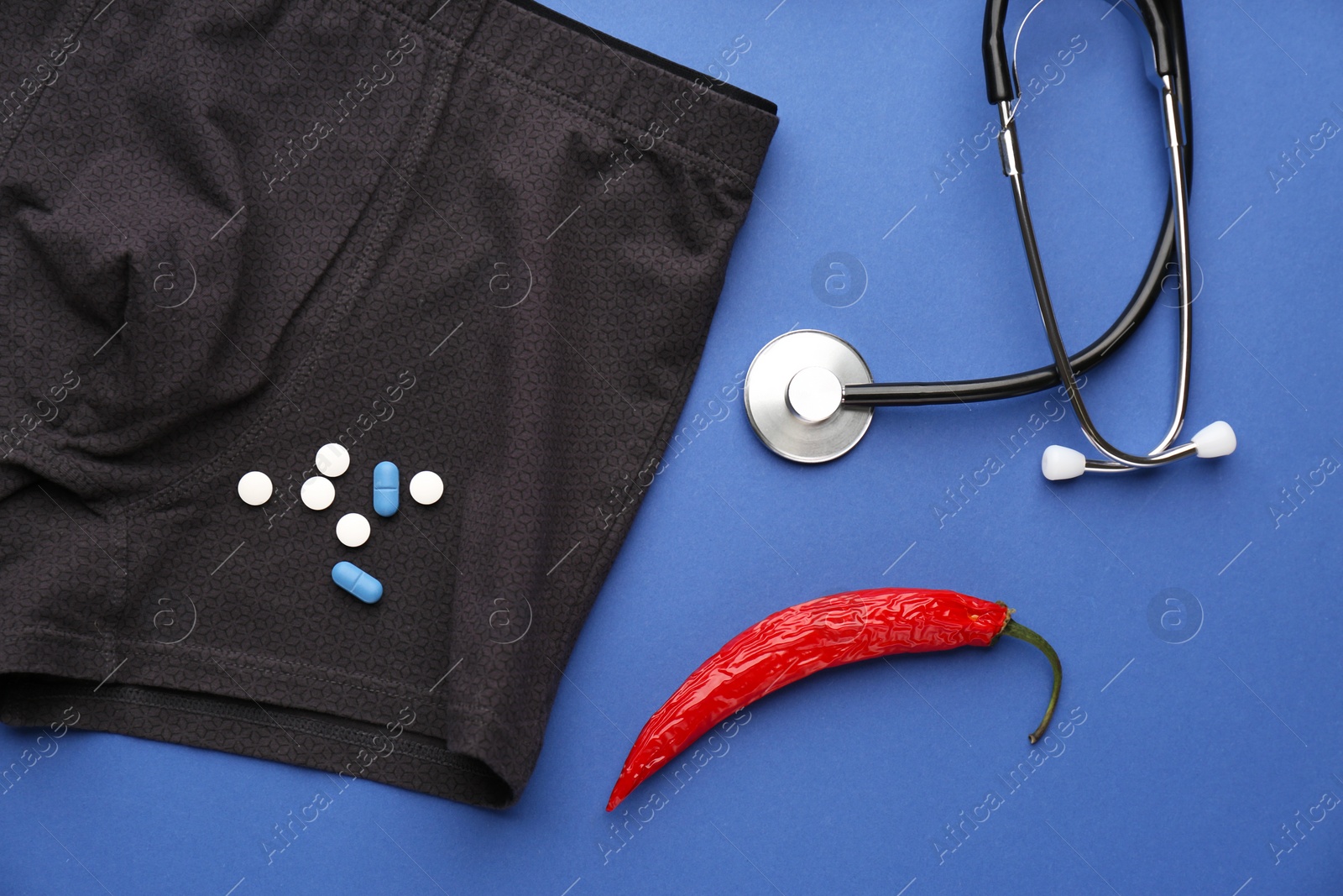 Photo of Flat lay composition with men's underwear and chili pepper on blue background. Potency problem concept