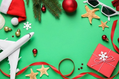 Photo of Frame of Christmas decorations, toy airplane and space for text on green background, flat lay. Winter vacation