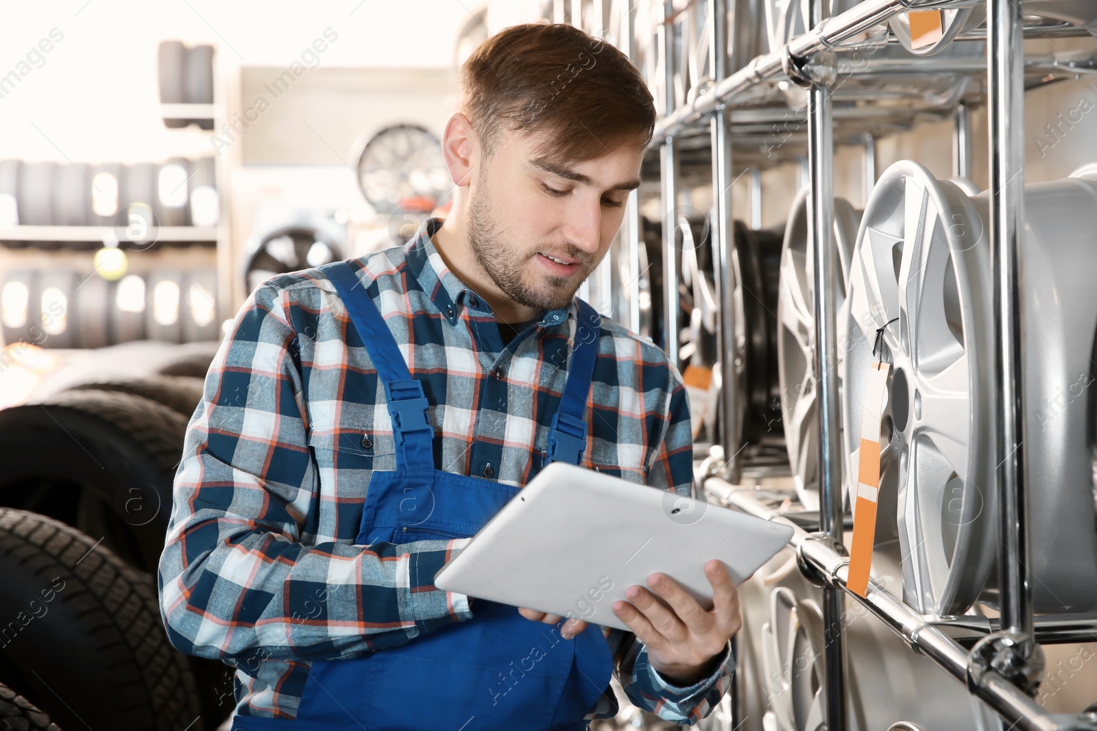 Photo of Young male mechanic with tablet computer in automobile service center