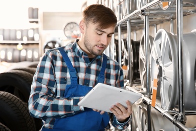 Young male mechanic with tablet computer in automobile service center