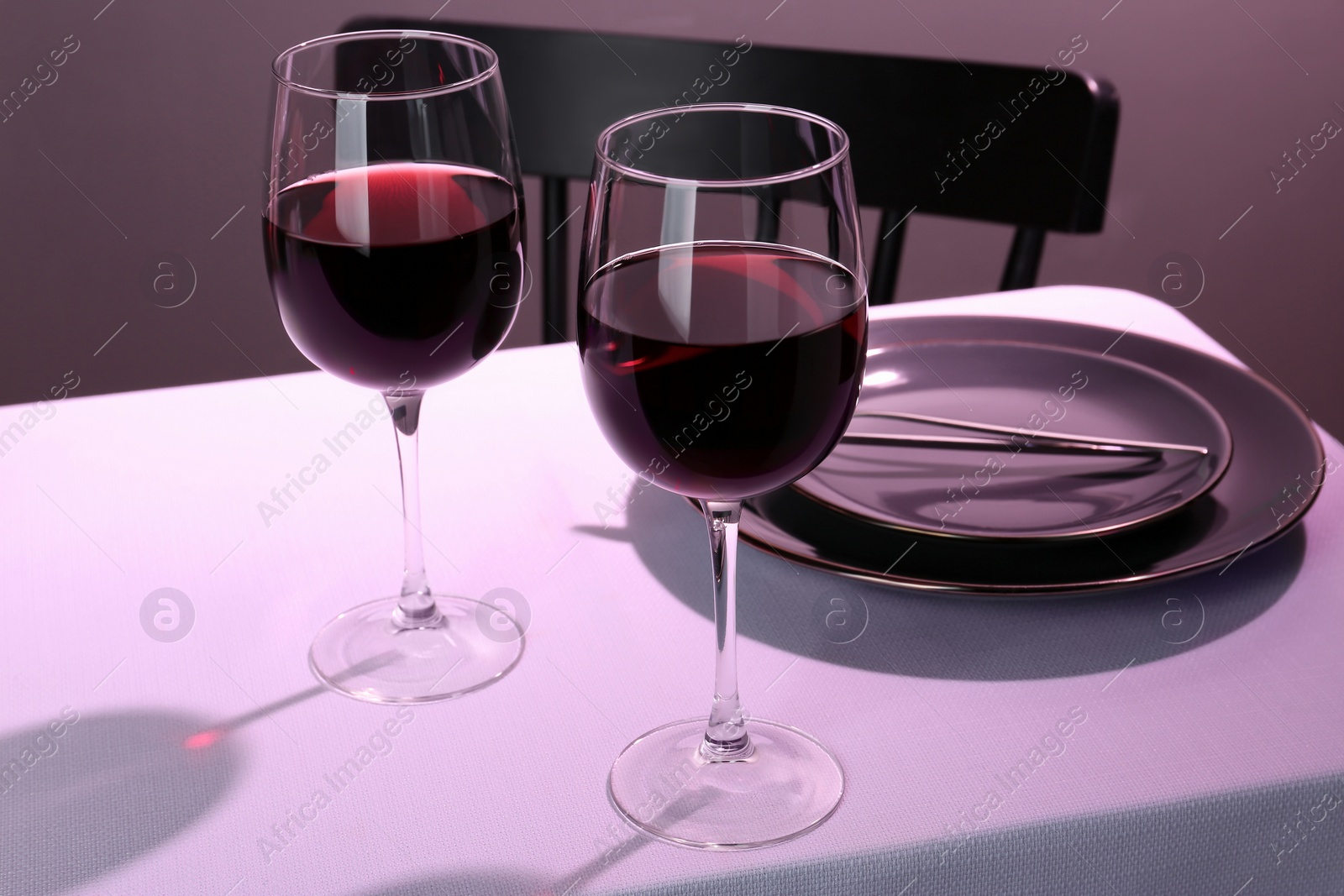 Photo of Romantic table setting with glasses of red wine indoors