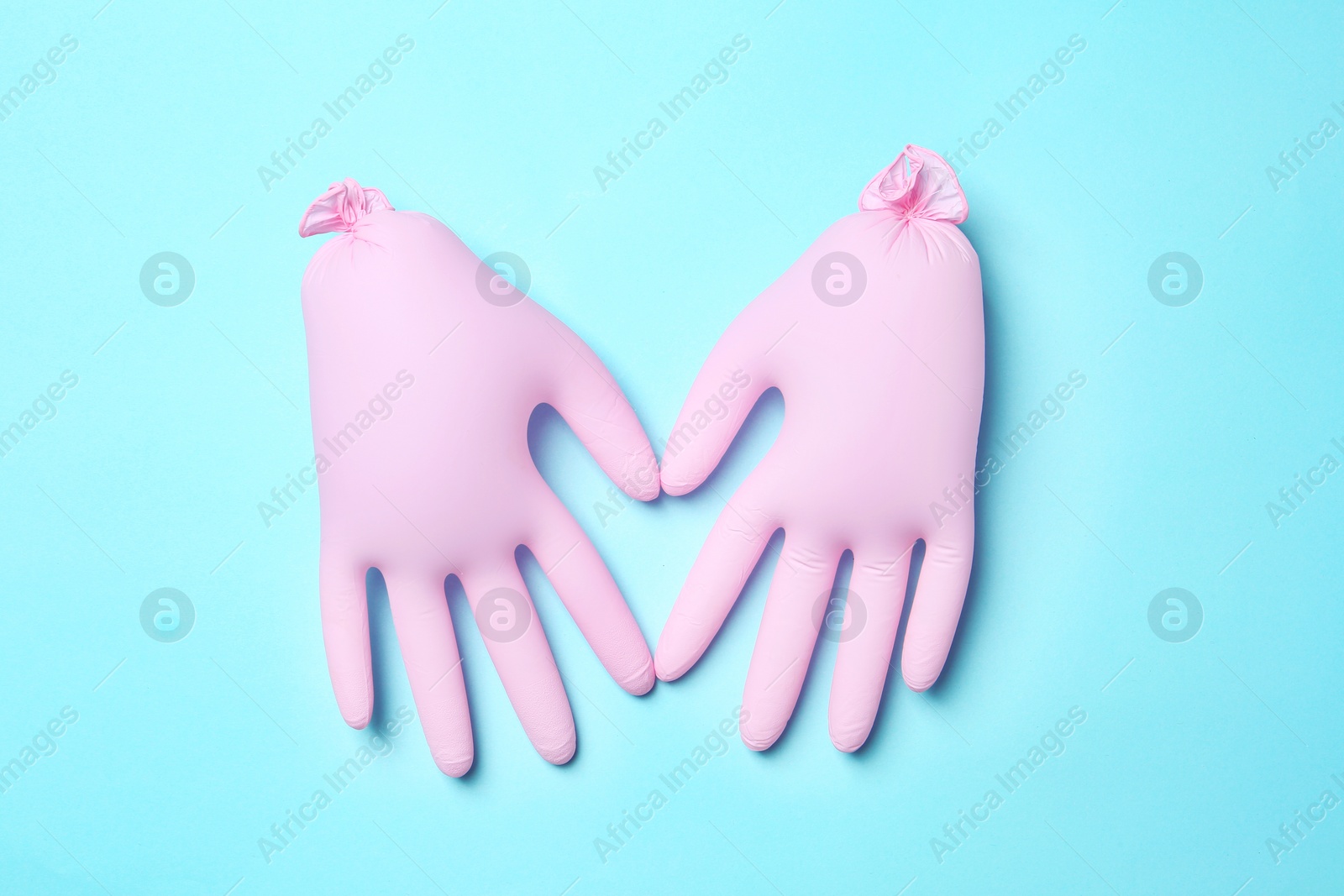 Photo of Inflated medical gloves on color background, top view