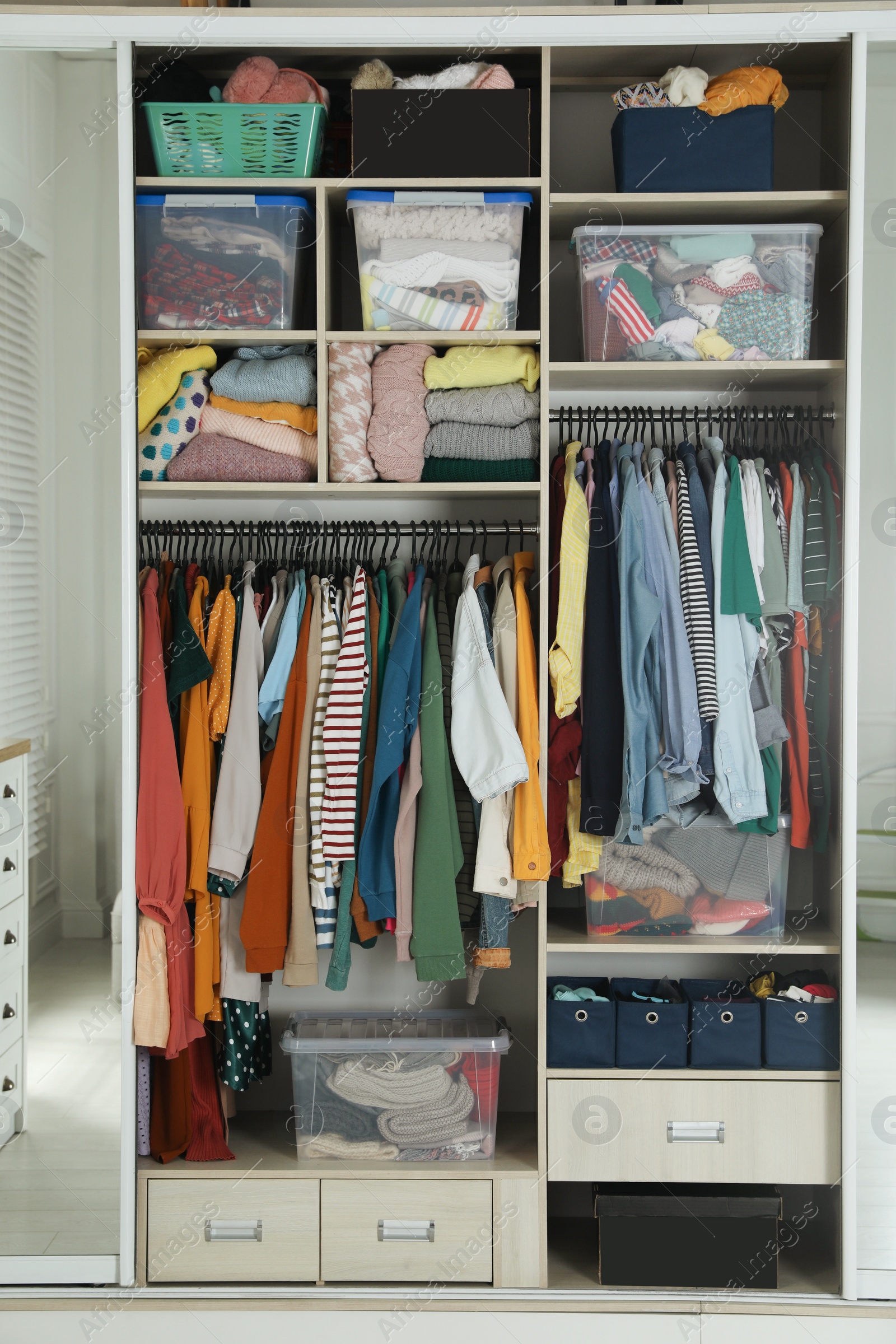 Photo of Wardrobe closet with different stylish clothes and home stuff in room. Fast fashion