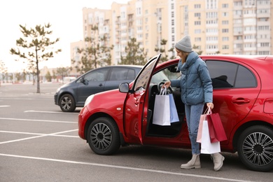 Photo of Woman with shopping bags near her car outdoors