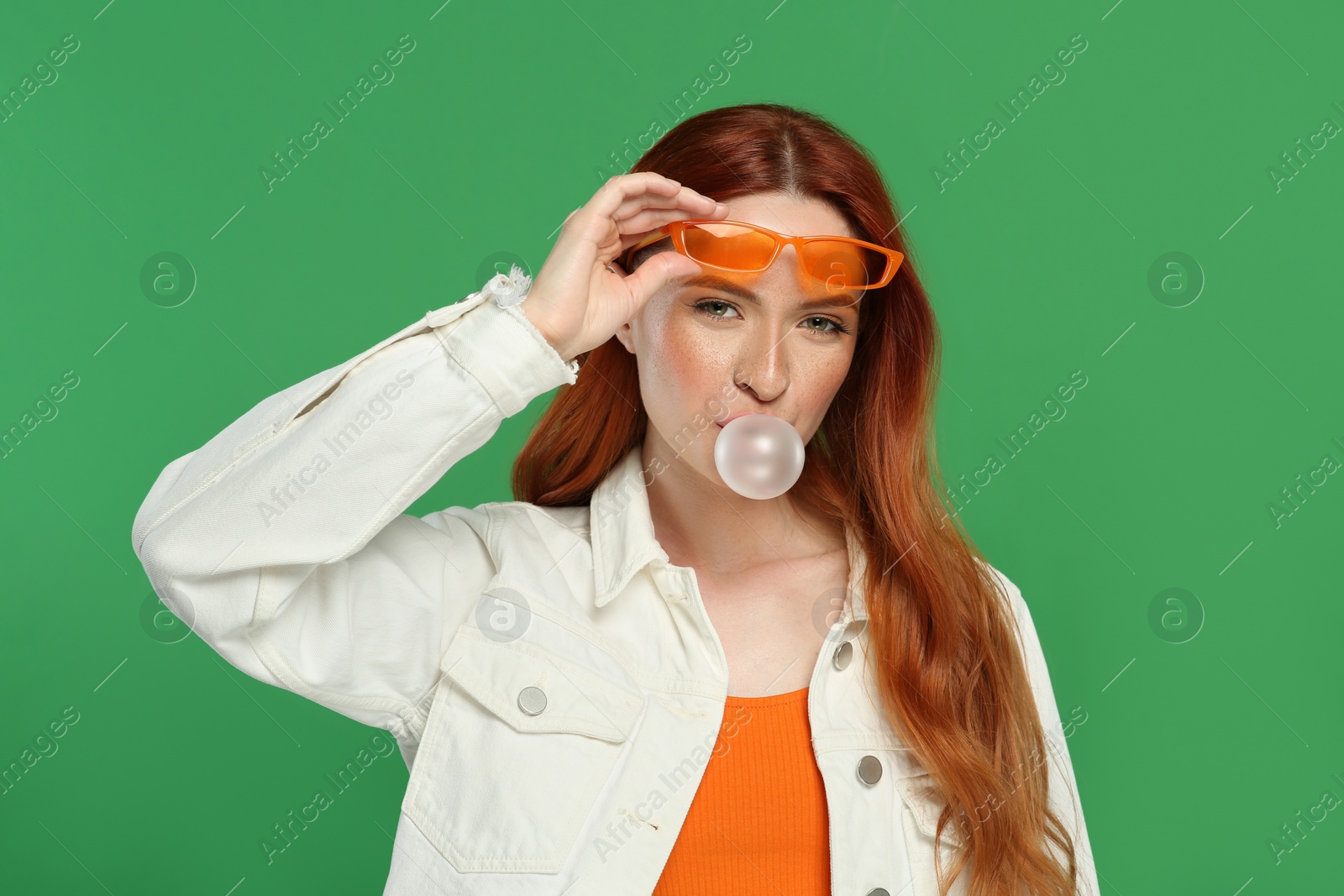 Photo of Portrait of beautiful woman blowing bubble gum on green background