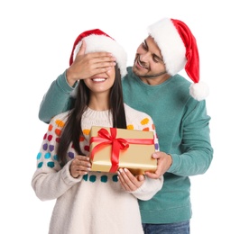 Photo of Young man giving gift box to his girlfriend on white background. Christmas celebration