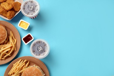 Photo of Different fast food on turquoise background, flat lay. Space for text
