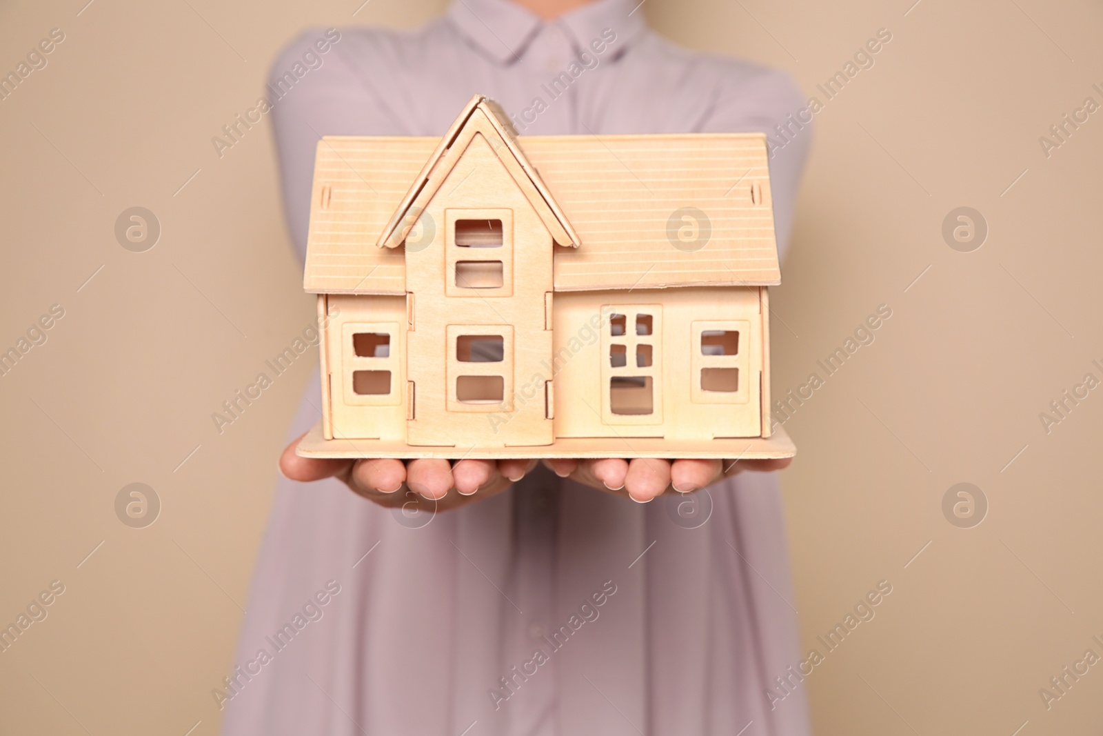 Photo of Young woman holding house model on color background, closeup