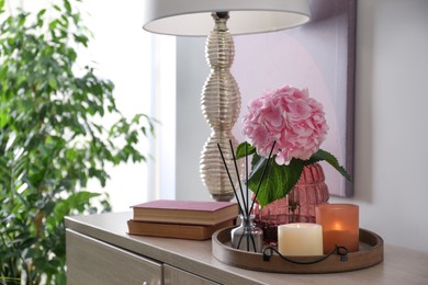 Photo of Stylish tray with different interior elements and lamp on chest of drawers indoors