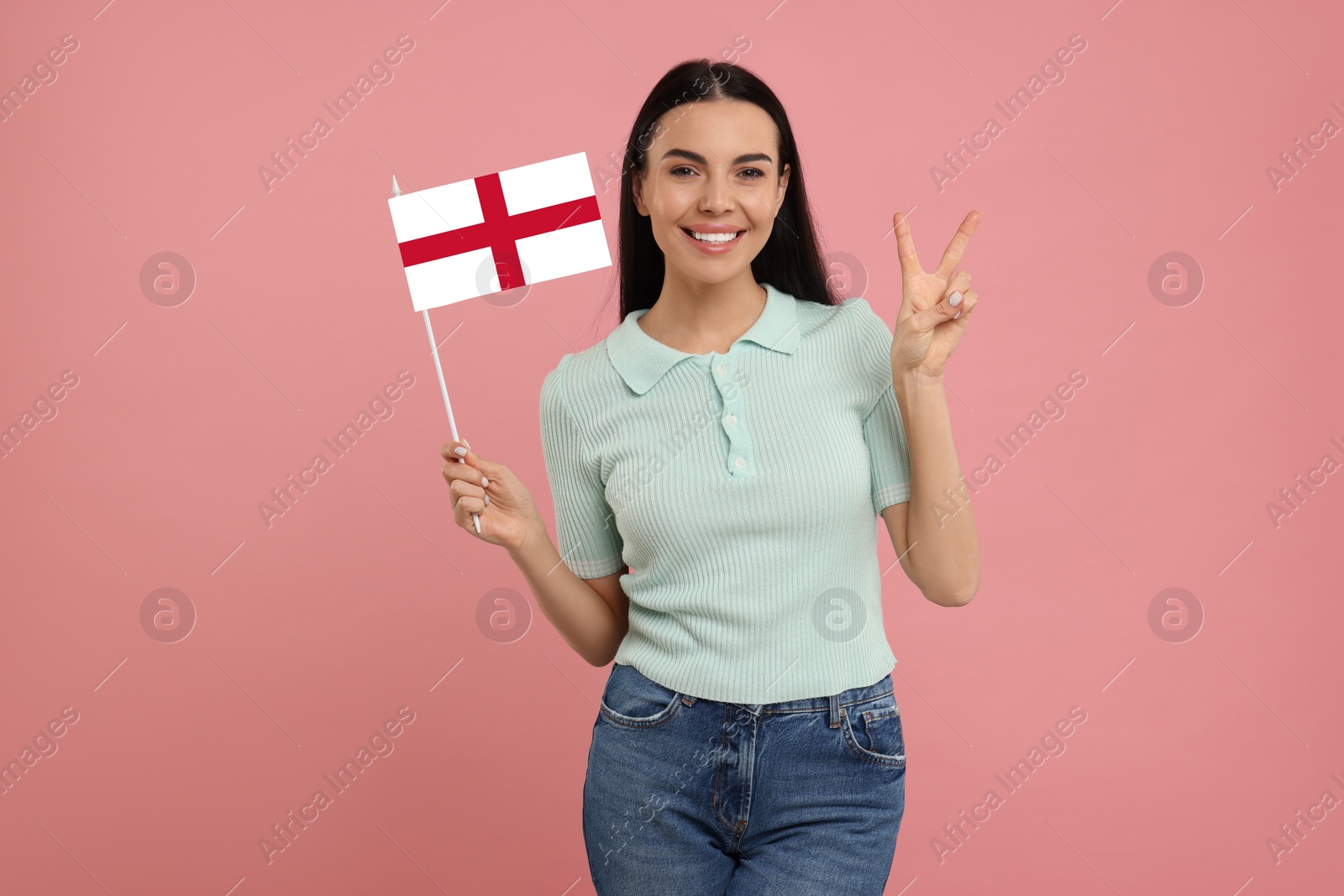 Image of Happy young woman with flag of England showing V-sign on pink background