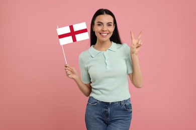 Image of Happy young woman with flag of England showing V-sign on pink background