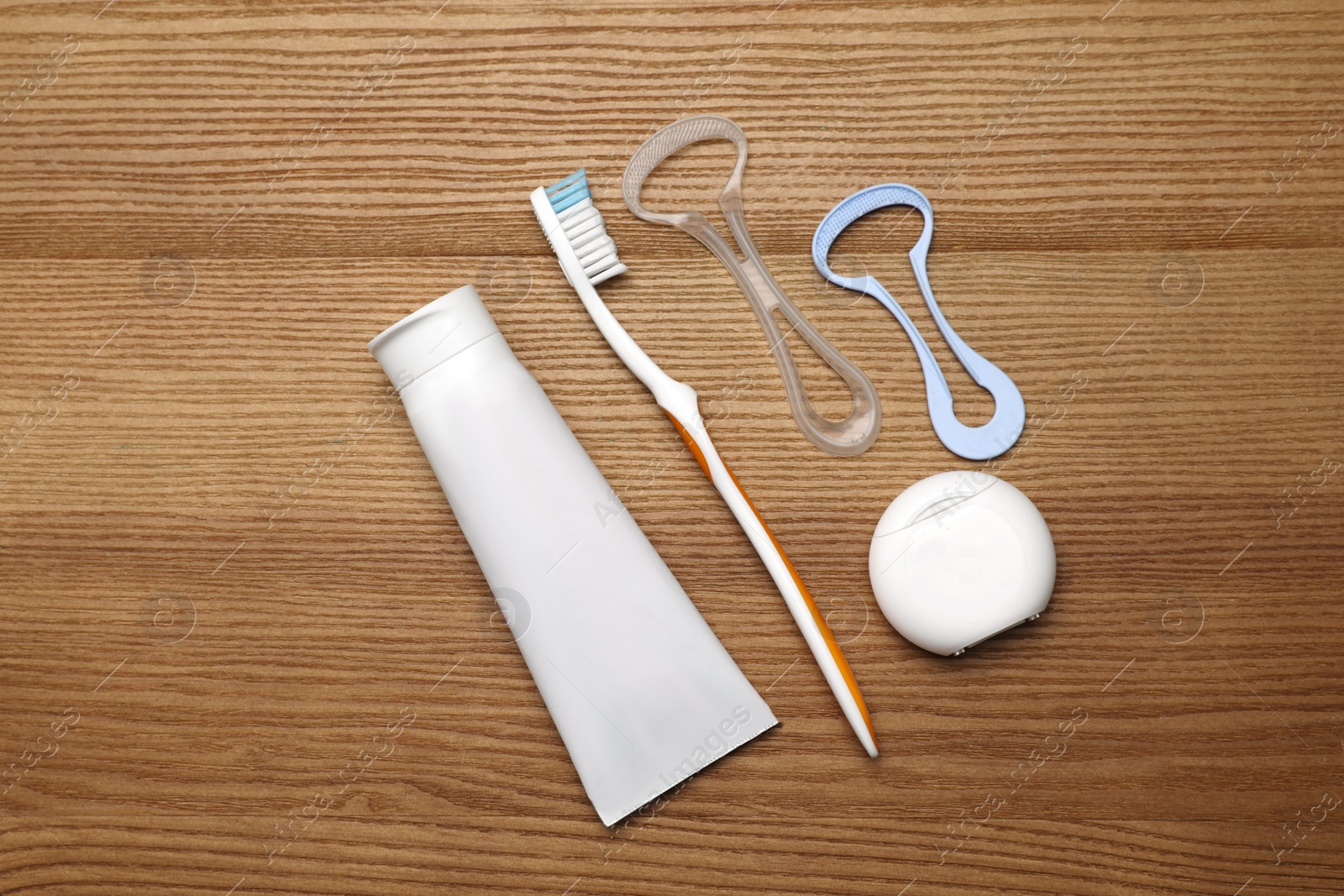 Photo of Flat lay composition with tongue cleaners and teeth care products on wooden table