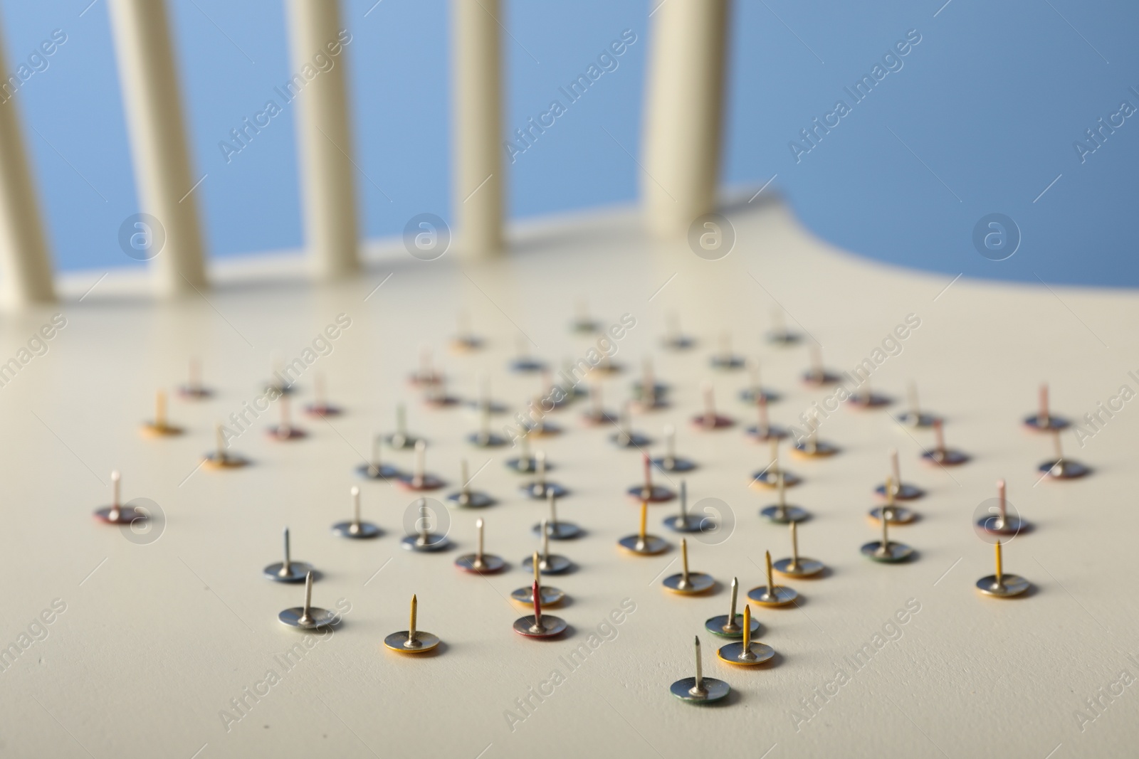 Photo of Chair with pins on blue background, closeup. April fool's day