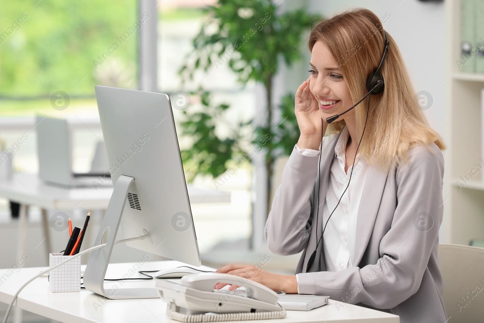 Photo of Female receptionist with headset at desk in office